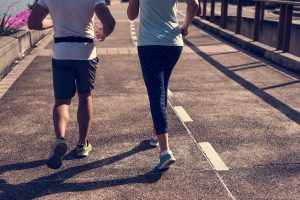 A man and woman jogging on a bike path during the day time.