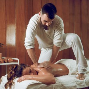 Woman laying on a massage table enjoying a deep tissue massage from a male masseuse  One of the many holistic procedures covered by Nova Path FInder 