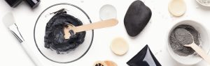 Two-bowls-of-activated-charcoal-stirred-up-next-to-makeup-brushes