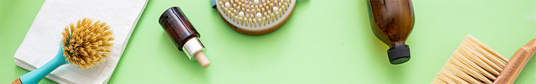 three different exfoliating brushes and two vials of essentia oil laying on a green table