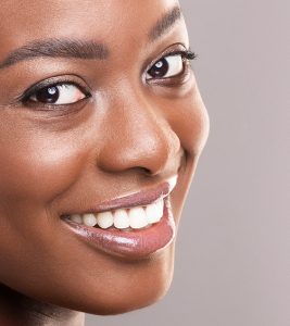 A woman's head shot smiling perfect white teeth into the camera