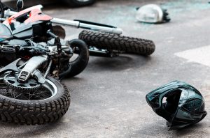 motorcycle crashed on the asphalt with a helmet lying next to it