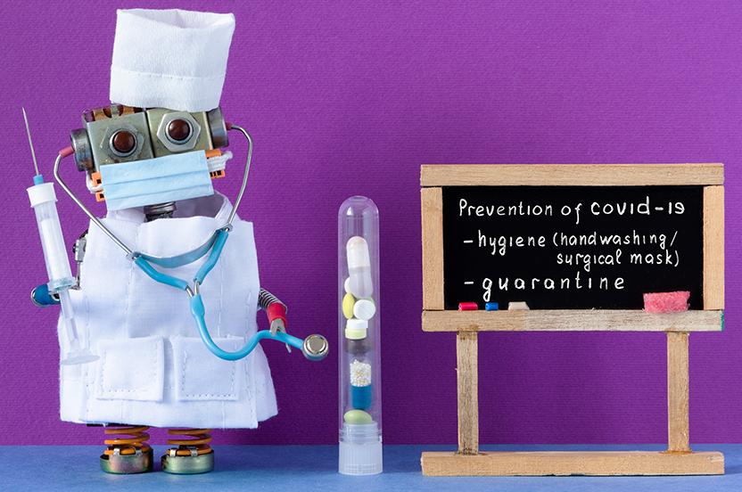 little robot wearing a surgical mask, smock, and hait holding a needle and stetloscope. Standing nect to a blackboard made of popsicle sticks that have "prevention of Covid-19; hygene (handwashing/surgical mask and quarintine written on it"